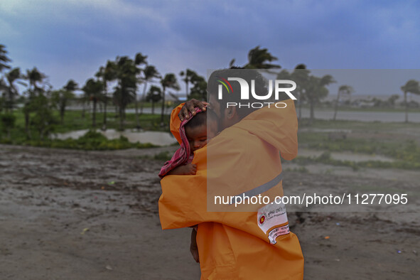 A volunteer is carrying a baby girl to take shelter in the Cyclone Shelter in Kuakata, Bangladesh, on May 26, 2024, ahead of cyclone Remal's...