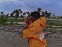 A volunteer is carrying a baby girl to take shelter in the Cyclone Shelter in Kuakata, Bangladesh, on May 26, 2024, ahead of cyclone Remal's...