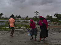 People with their belongings are walking towards a shelter during a rainfall in Kuakata, Bangladesh, on May 26, 2024, ahead of cyclone Remal...