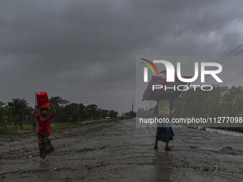 People with their belongings are walking towards a shelter during a rainfall in Kuakata, Bangladesh, on May 26, 2024, ahead of cyclone Remal...