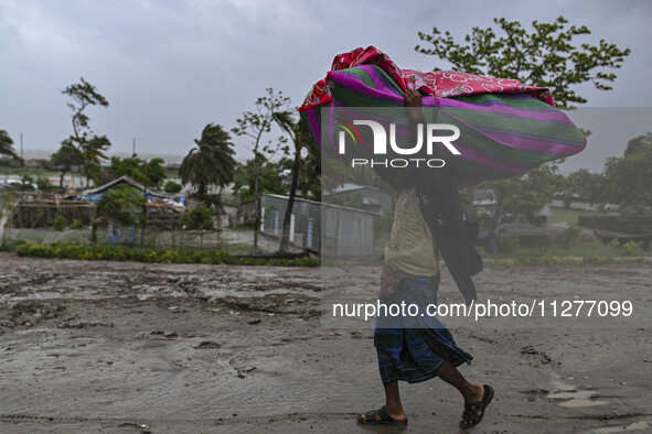 A man is walking with his belongings towards a shelter during a rainfall in Kuakata, Bangladesh, on May 26, 2024, ahead of cyclone Remal's l...