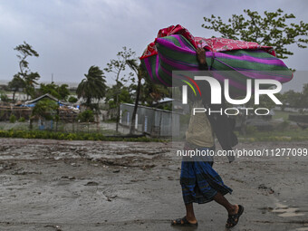 A man is walking with his belongings towards a shelter during a rainfall in Kuakata, Bangladesh, on May 26, 2024, ahead of cyclone Remal's l...