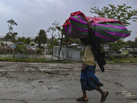 A man is walking with his belongings towards a shelter during a rainfall in Kuakata, Bangladesh, on May 26, 2024, ahead of cyclone Remal's l...