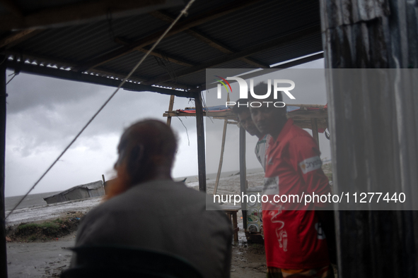 People are taking shelter during a heavy rainfall at Kuakata Sea Beach area in southern Bangladesh on May 26, 2024, as Cyclone Remal nears. 