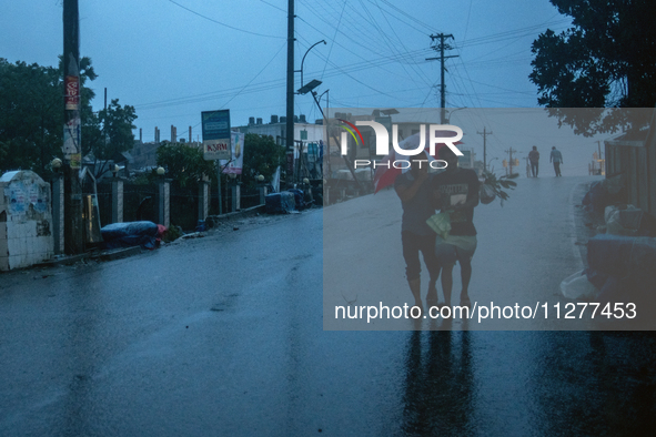 People are walking through light rain and wind as Cyclone Remal is making landfall at Kuakata Sea Beach in southern Bangladesh on May 26, 20...