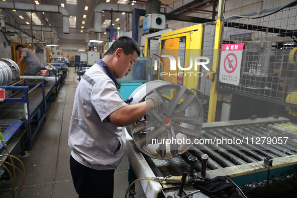 A worker is producing a wheel hub at a workshop of an automobile wheel manufacturer in Binzhou, China, on May 27, 2024. 