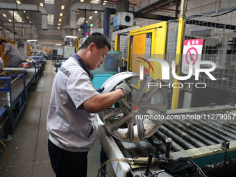 A worker is producing a wheel hub at a workshop of an automobile wheel manufacturer in Binzhou, China, on May 27, 2024. (