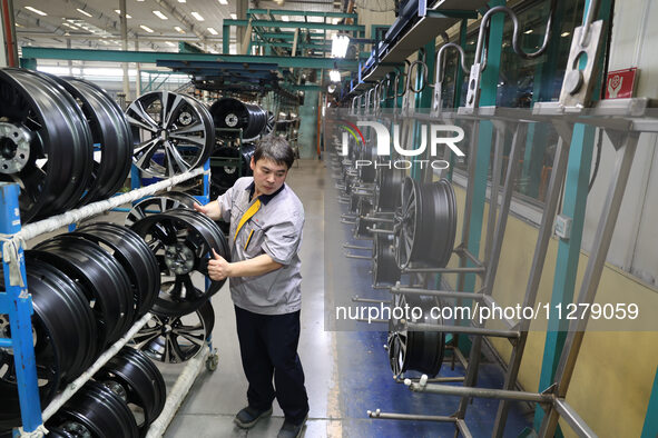 A worker is producing a wheel hub at a workshop of an automobile wheel manufacturer in Binzhou, China, on May 27, 2024. 