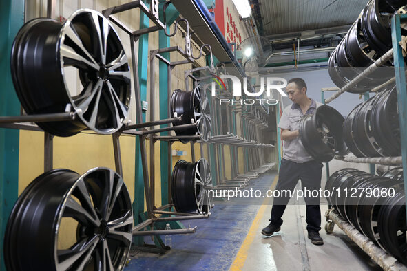 A worker is producing a wheel hub at a workshop of an automobile wheel manufacturer in Binzhou, China, on May 27, 2024. 