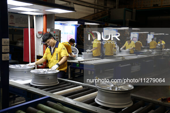 Workers are producing wheels at a workshop of an automobile wheel manufacturer in Binzhou, China, on May 27, 2024. 