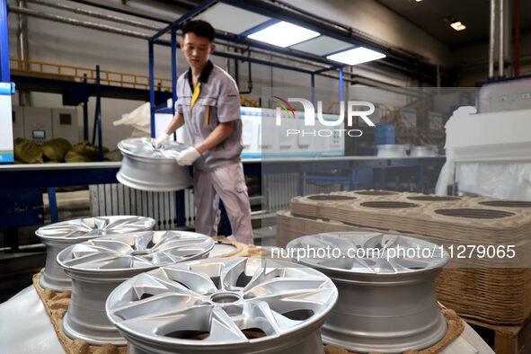 A worker is producing a wheel hub at a workshop of an automobile wheel manufacturer in Binzhou, China, on May 27, 2024. 