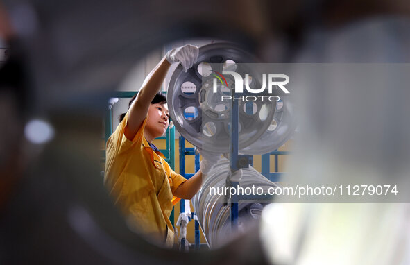 A worker is producing a wheel hub at a workshop of an automobile wheel manufacturer in Binzhou, China, on May 27, 2024. 