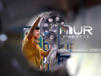 A worker is producing a wheel hub at a workshop of an automobile wheel manufacturer in Binzhou, China, on May 27, 2024. (