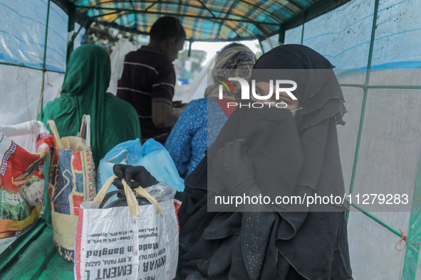 A woman is boarding a van covered by plastic to reach a cyclone shelter center as Cyclone Remal is landing in Satkhura, Bangladesh, on May 2...