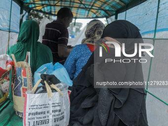 A woman is boarding a van covered by plastic to reach a cyclone shelter center as Cyclone Remal is landing in Satkhura, Bangladesh, on May 2...