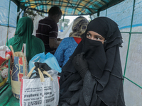 A woman is boarding a van covered by plastic to reach a cyclone shelter center as Cyclone Remal is landing in Satkhura, Bangladesh, on May 2...