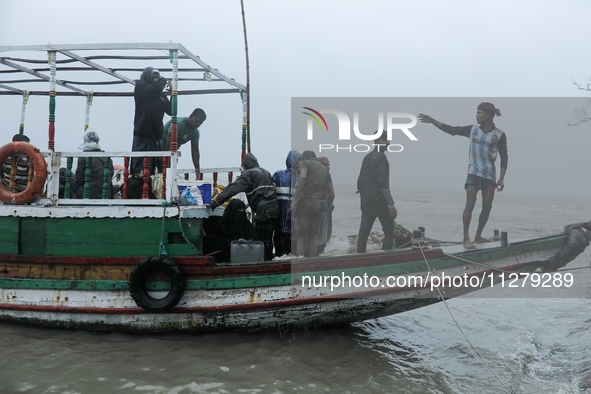 People are boarding a boat to reach a cyclone shelter center as Cyclone Remal is landing in Satkhura, Bangladesh, on May 27, 2024 