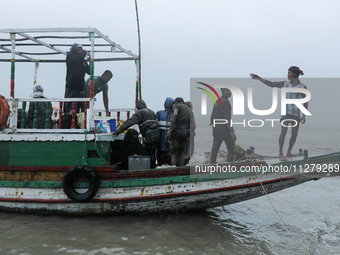 People are boarding a boat to reach a cyclone shelter center as Cyclone Remal is landing in Satkhura, Bangladesh, on May 27, 2024 (