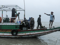 People are boarding a boat to reach a cyclone shelter center as Cyclone Remal is landing in Satkhura, Bangladesh, on May 27, 2024 (