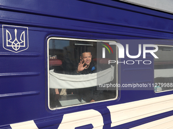 A boy is waving goodbye from a sleeper car as families with children evacuated from the frontline areas of Kharkiv region are going on vacat...