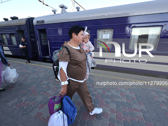 A woman is carrying a baby along the platform as families with children evacuated from the frontline areas of Kharkiv region are going on va...