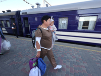 A woman is carrying a baby along the platform as families with children evacuated from the frontline areas of Kharkiv region are going on va...