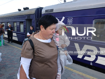 A woman is carrying a baby along the platform as families with children evacuated from the frontline areas of Kharkiv region are going on va...