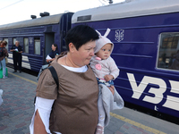 A woman is carrying a baby along the platform as families with children evacuated from the frontline areas of Kharkiv region are going on va...