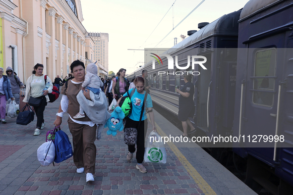 A woman is carrying a baby along the platform as families with children evacuated from the frontline areas of Kharkiv region are going on va...