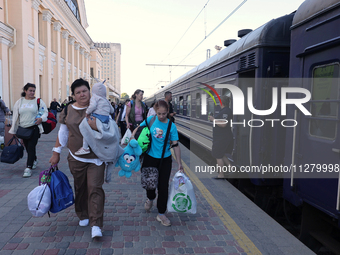 A woman is carrying a baby along the platform as families with children evacuated from the frontline areas of Kharkiv region are going on va...