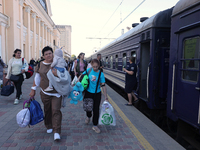 A woman is carrying a baby along the platform as families with children evacuated from the frontline areas of Kharkiv region are going on va...