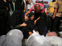 People are mourning by the bodies of relatives killed after Israeli bombardment hit a family home in Nuseirat, at the Al-Aqsa Martyrs Hospit...