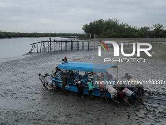 Villagers are pushing a speedboat through mud to rescue wildlife trapped amidst Cyclone Remal in Satkhira, Bangladesh, on May 28, 2024. (