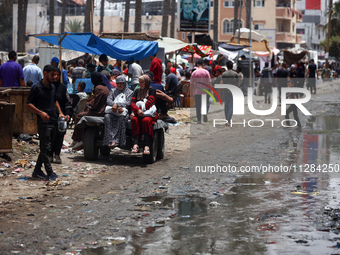 Displaced Palestinians are walking near sewage water in Deir el-Balah in the central Gaza Strip on May 28, 2024, amid the ongoing conflict b...