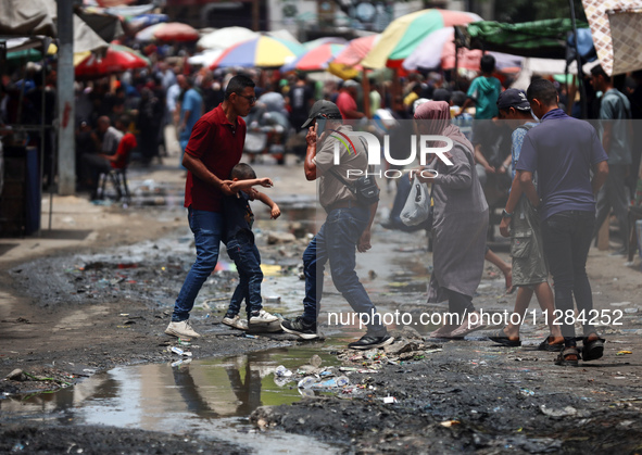 Displaced Palestinians are walking near sewage water in Deir el-Balah in the central Gaza Strip on May 28, 2024, amid the ongoing conflict b...