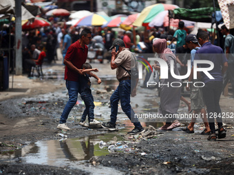 Displaced Palestinians are walking near sewage water in Deir el-Balah in the central Gaza Strip on May 28, 2024, amid the ongoing conflict b...