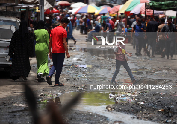 Displaced Palestinians are walking near sewage water in Deir el-Balah in the central Gaza Strip on May 28, 2024, amid the ongoing conflict b...