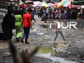 Displaced Palestinians are walking near sewage water in Deir el-Balah in the central Gaza Strip on May 28, 2024, amid the ongoing conflict b...