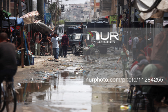 Displaced Palestinians are walking near sewage water in Deir el-Balah in the central Gaza Strip on May 28, 2024, amid the ongoing conflict b...