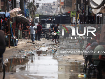 Displaced Palestinians are walking near sewage water in Deir el-Balah in the central Gaza Strip on May 28, 2024, amid the ongoing conflict b...