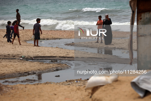 Displaced Palestinians are walking near sewage water in Deir el-Balah in the central Gaza Strip on May 28, 2024, amid the ongoing conflict b...