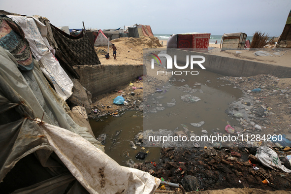 Displaced Palestinians are walking near sewage water in Deir el-Balah in the central Gaza Strip on May 28, 2024, amid the ongoing conflict b...