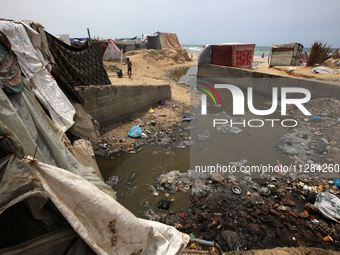 Displaced Palestinians are walking near sewage water in Deir el-Balah in the central Gaza Strip on May 28, 2024, amid the ongoing conflict b...