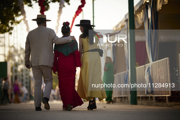 A group of people are walking through the fairgrounds at sunset during the festivities of the Corpus Christi in Granada, Spain, on May 28, 2...