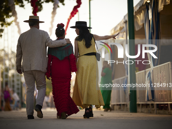 A group of people are walking through the fairgrounds at sunset during the festivities of the Corpus Christi in Granada, Spain, on May 28, 2...