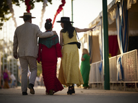 A group of people are walking through the fairgrounds at sunset during the festivities of the Corpus Christi in Granada, Spain, on May 28, 2...