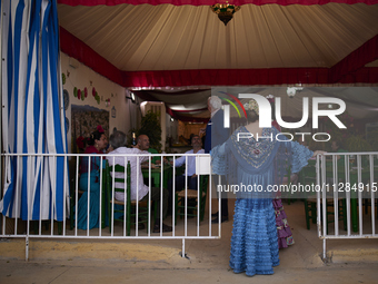 A woman dressed in a typical flamenco dress is talking to other people at the entrance to a ''caseta'' during the festivities of the Corpus...