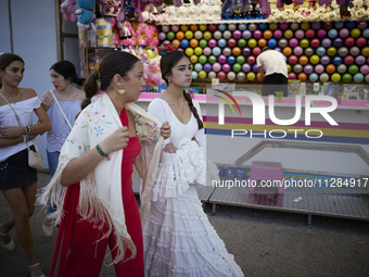 Two girls are wearing traditional flamenco dresses and walking during the festivities of the Corpus Christi in Granada, Spain, on May 28, 20...