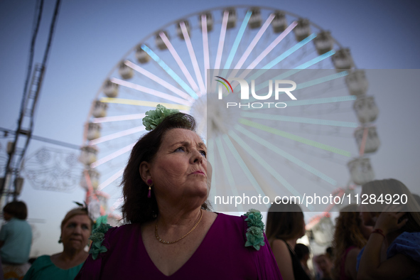 A woman is dressing in a typical flamenco dress and watching the swings at the fairgrounds during the festivities of the Corpus Christi in G...