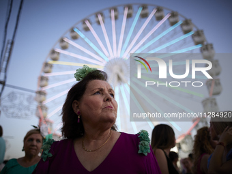 A woman is dressing in a typical flamenco dress and watching the swings at the fairgrounds during the festivities of the Corpus Christi in G...